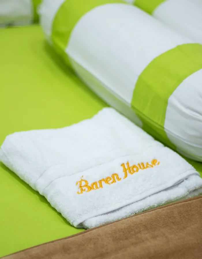 Handuk bersulam logo Baren House di atas kasur
